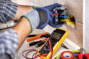 Electrician hands testing wiring with multimeter - Tritan Services electrical work Naperville