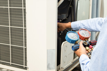 HVAC technician using gauges on AC unit - Tritan Services heating cooling Naperville