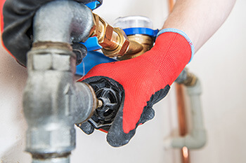 Plumber hands gripping copper pipe fitting - Tritan Services plumbing repair Naperville