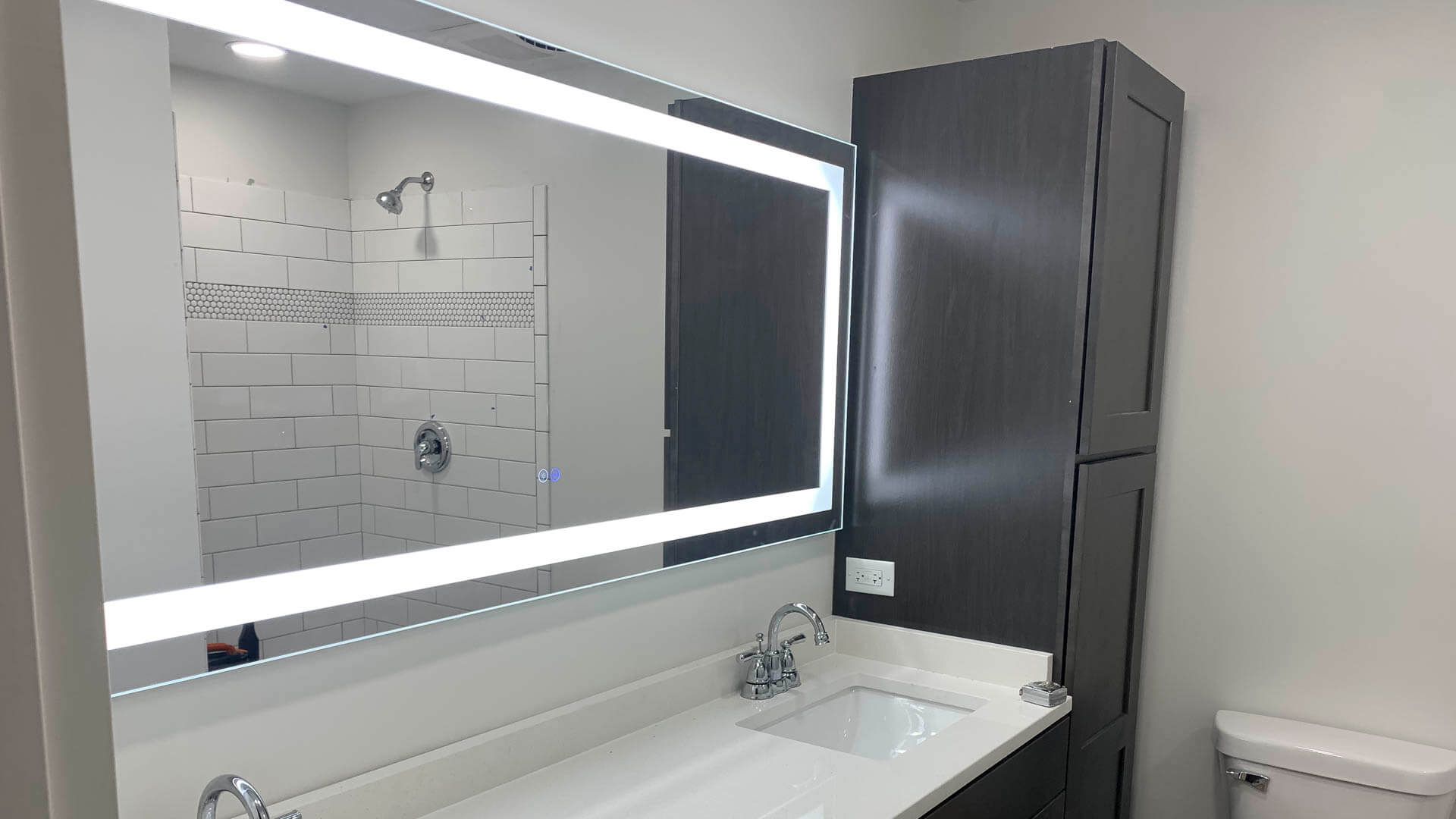 Double-sink bathroom vanity with backlit mirror lighting installed by Tritan