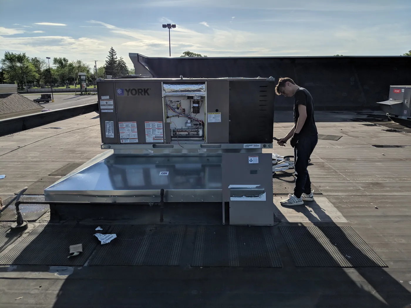 Technician installing a rooftop HVAC unit on a commercial building