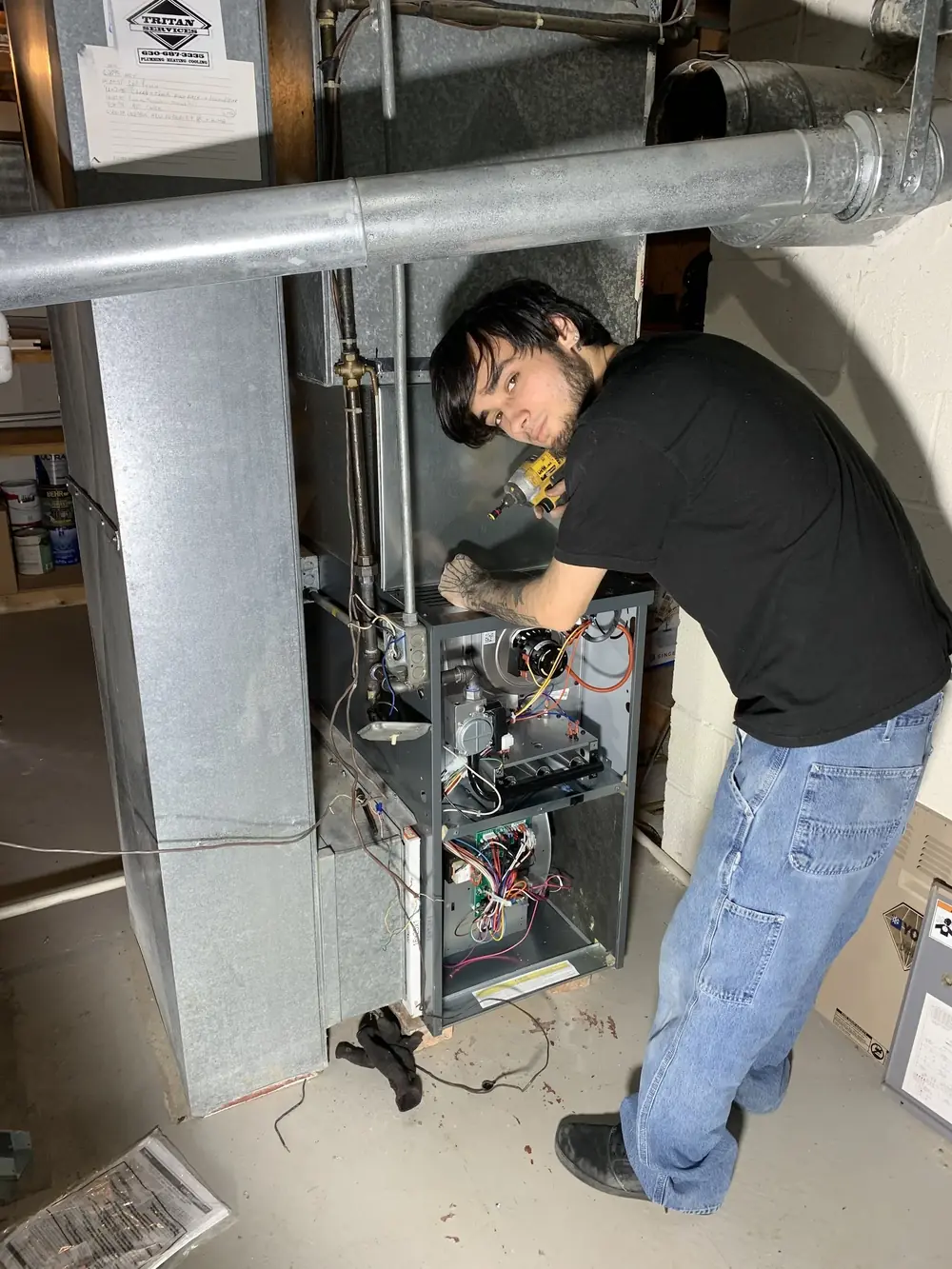 Tritan HVAC technician inspecting a furnace burner during install in Naperville