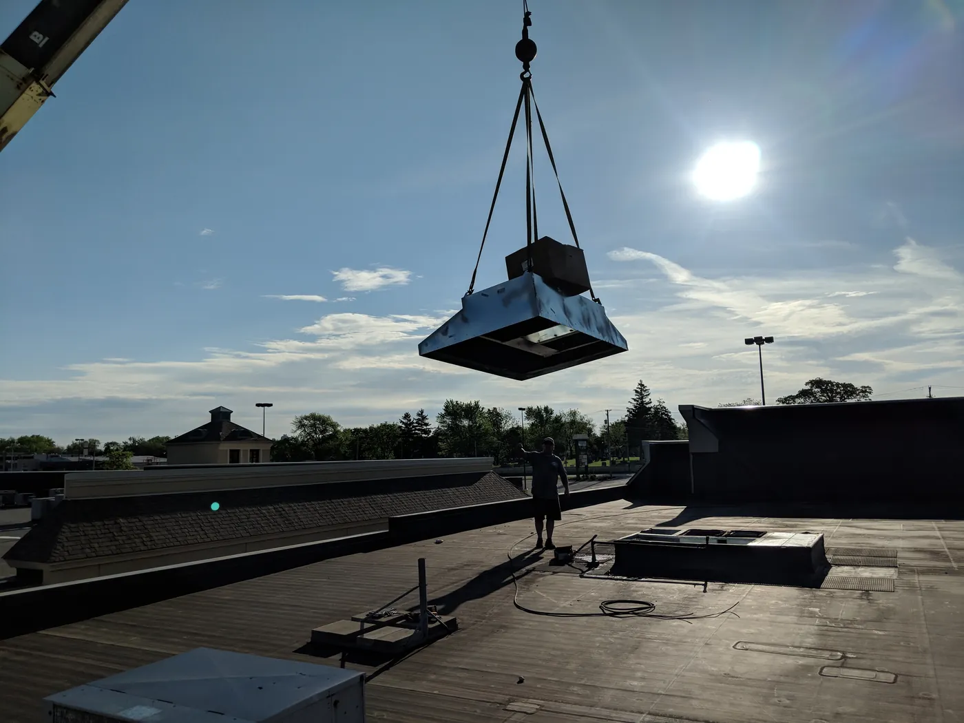 Crane setting a rooftop HVAC unit on a commercial roof